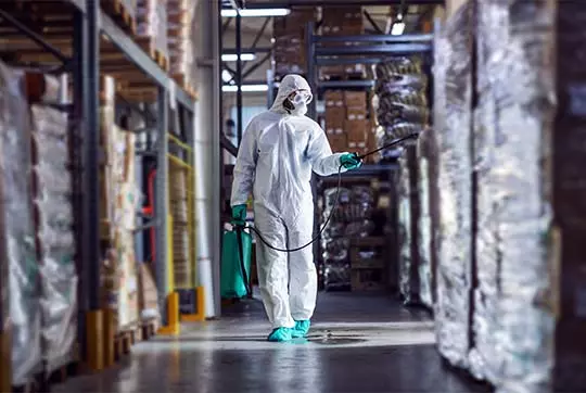 Warehouse pest control service in Noida – certified technician inspecting pallets, racking and storage aisles
